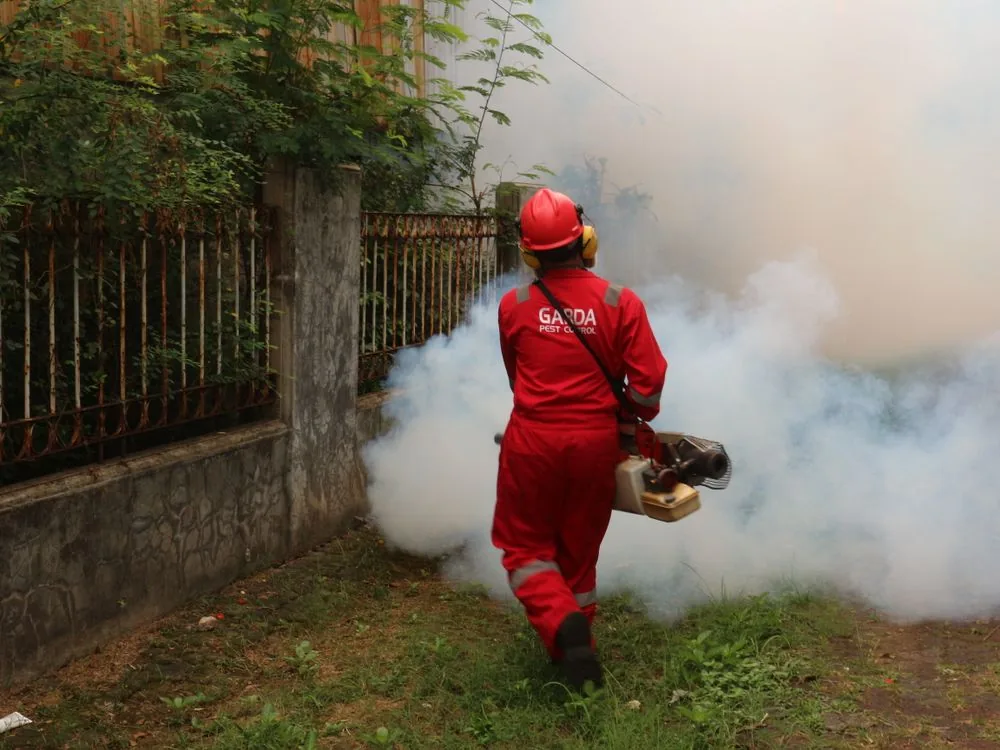 Technician with fogging equipment working outdoors along a fence line in Waco