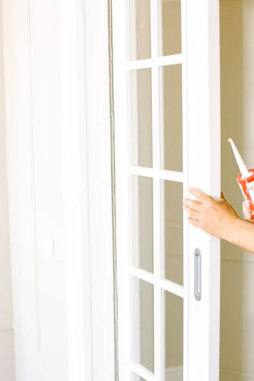 Person applying putty to seal a sliding door frame during home renovation in Waco