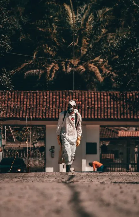 Technician in protective clothing walking outside a house in Waco during a service visit