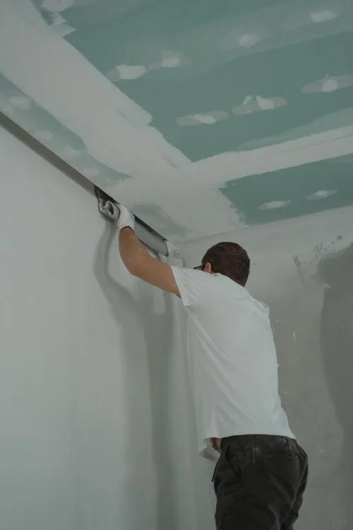 Worker installing drywall during a house renovation